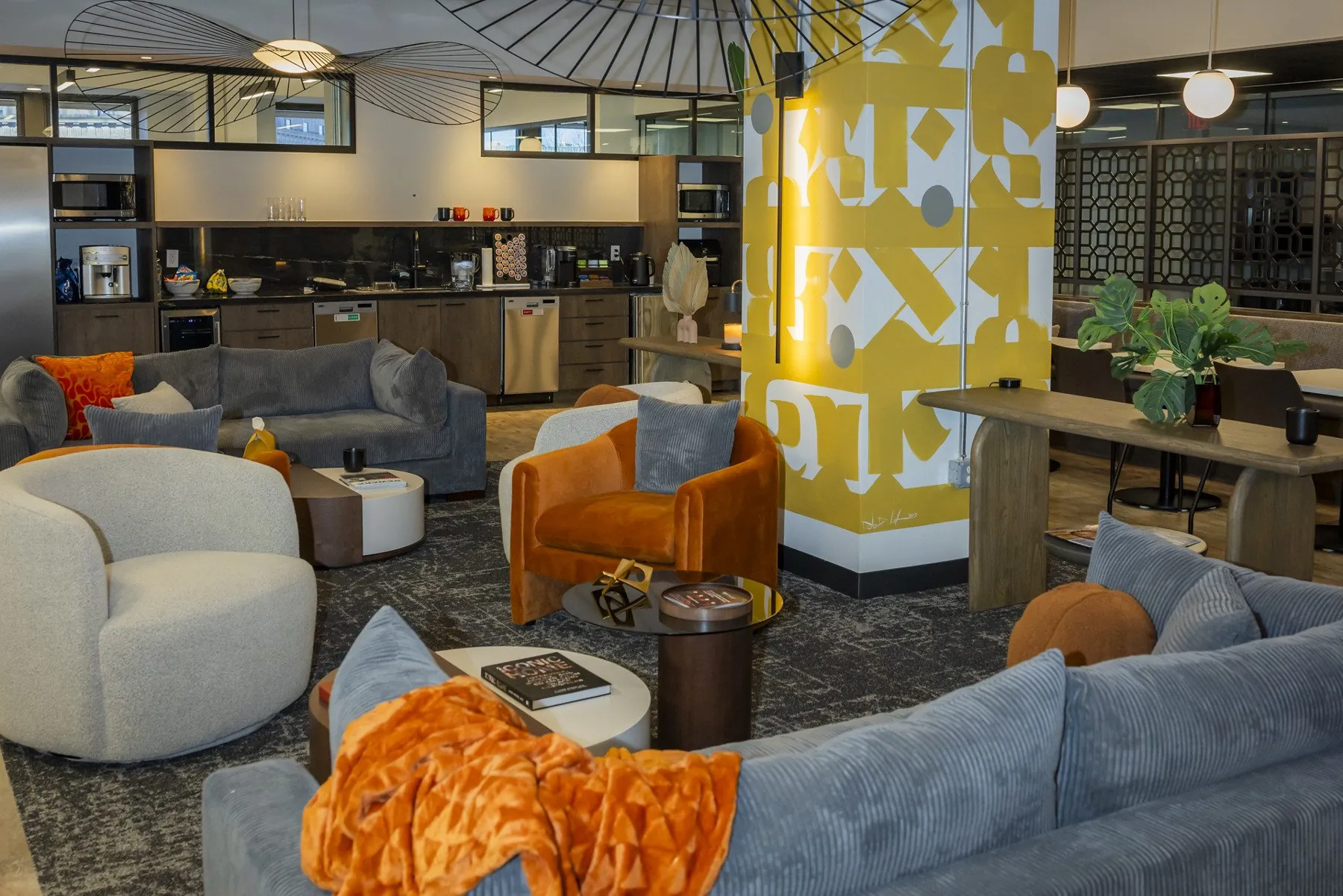 Lounge with curved gray sofas, orange throws, and a yellow patterned column