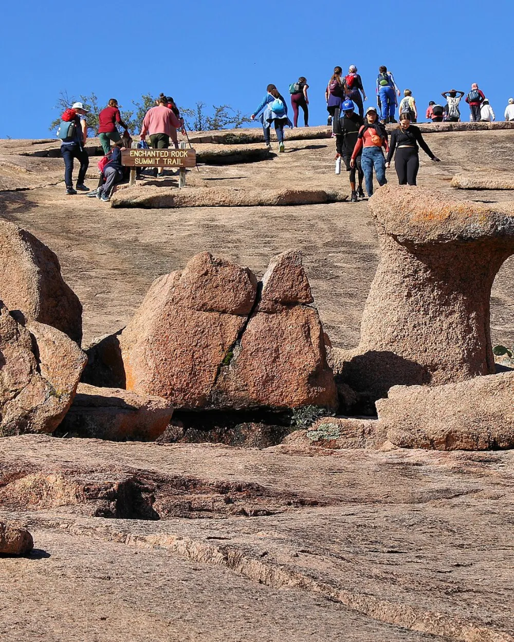 Hikers atop the billion-year-old pink granite dome of Enchanted Rock