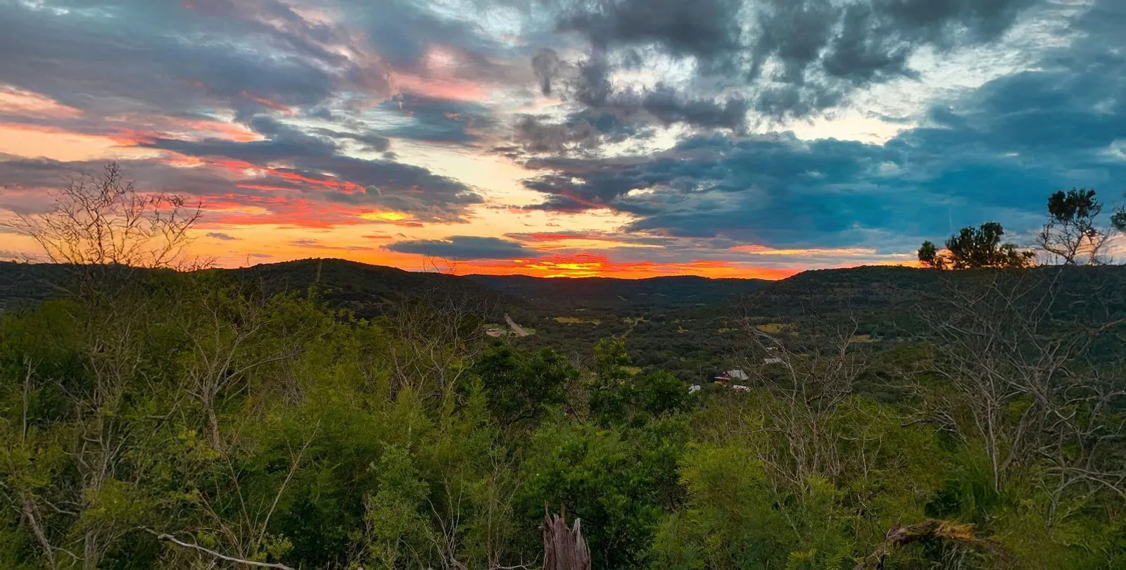 Sunset breaking orange over the rolling green hills of the Texas Hill Country