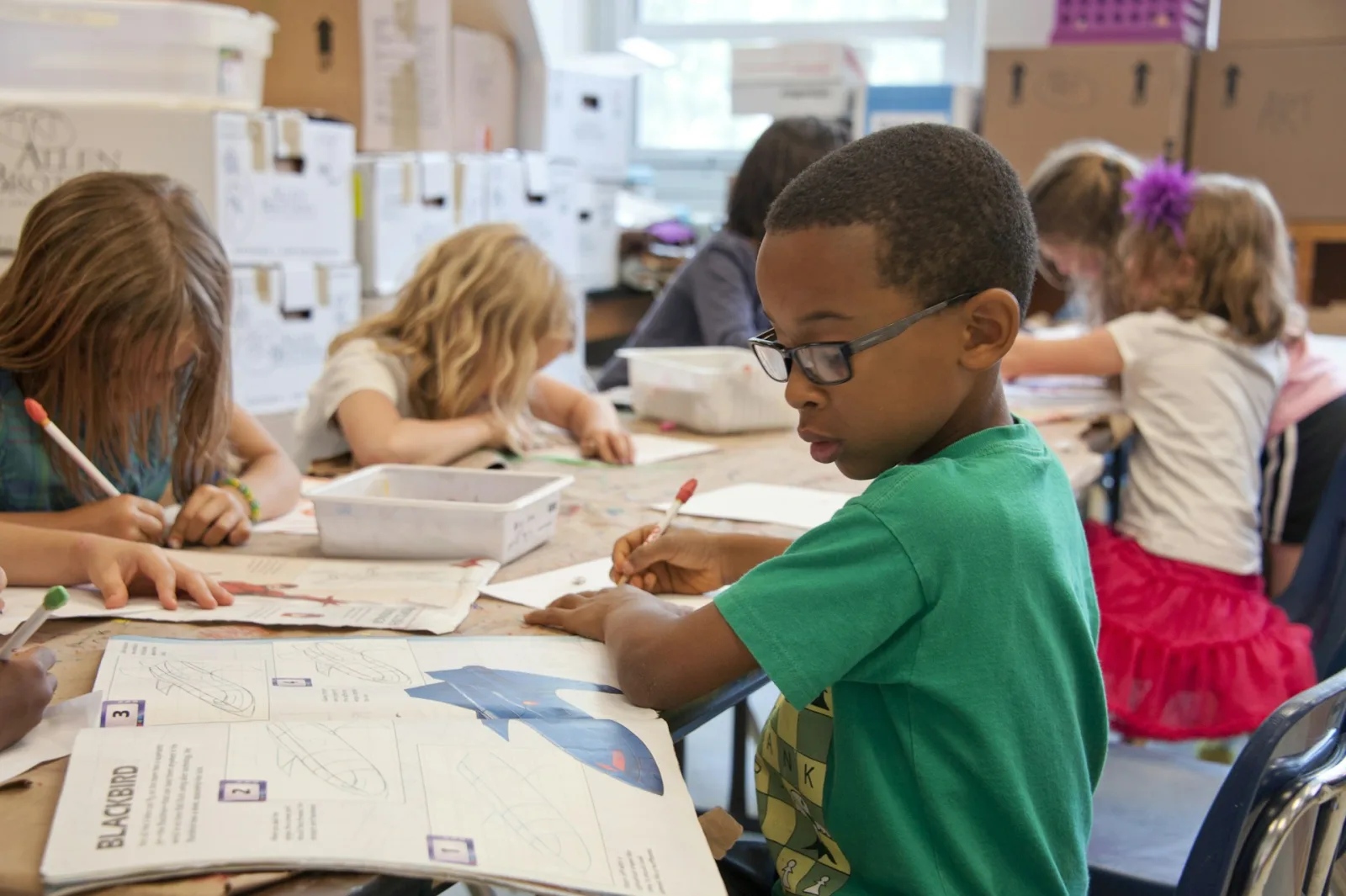 Child absorbed in a book at a classroom desk